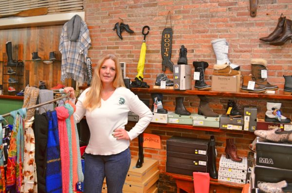 Cindy Brashear, owner of Cobblers Cottage, standing among the shop's winter boots collection.