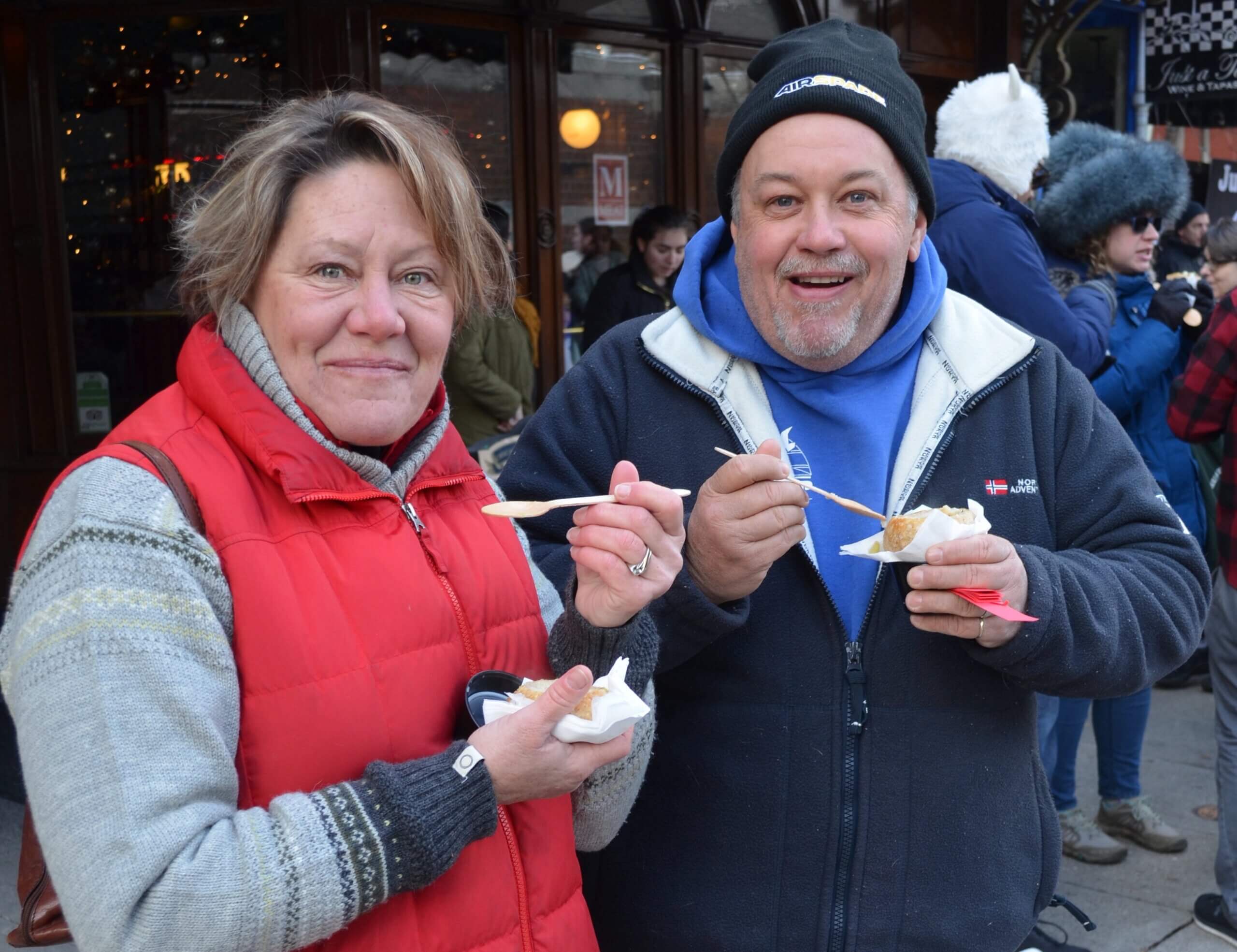 Participants in a past Chowder Cook-Off- man and woman eating chowder and smiling into camera