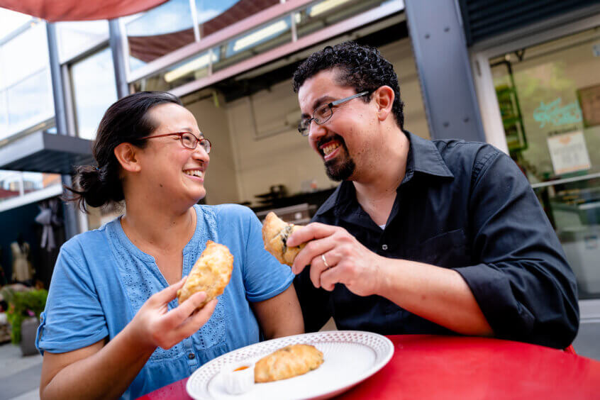 A woman and a man toasting with hand pies.