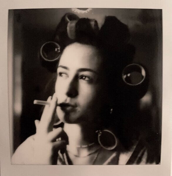 a photo of a woman in curlers (black and white image) smoking a cigarette